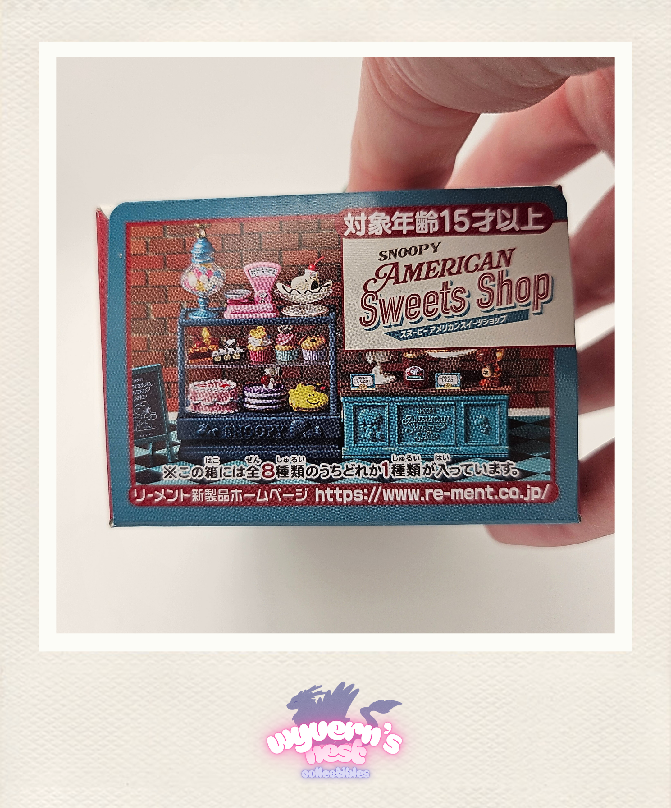 Miniature model of a SNOOPY American Sweets Shop with a hand holding it.