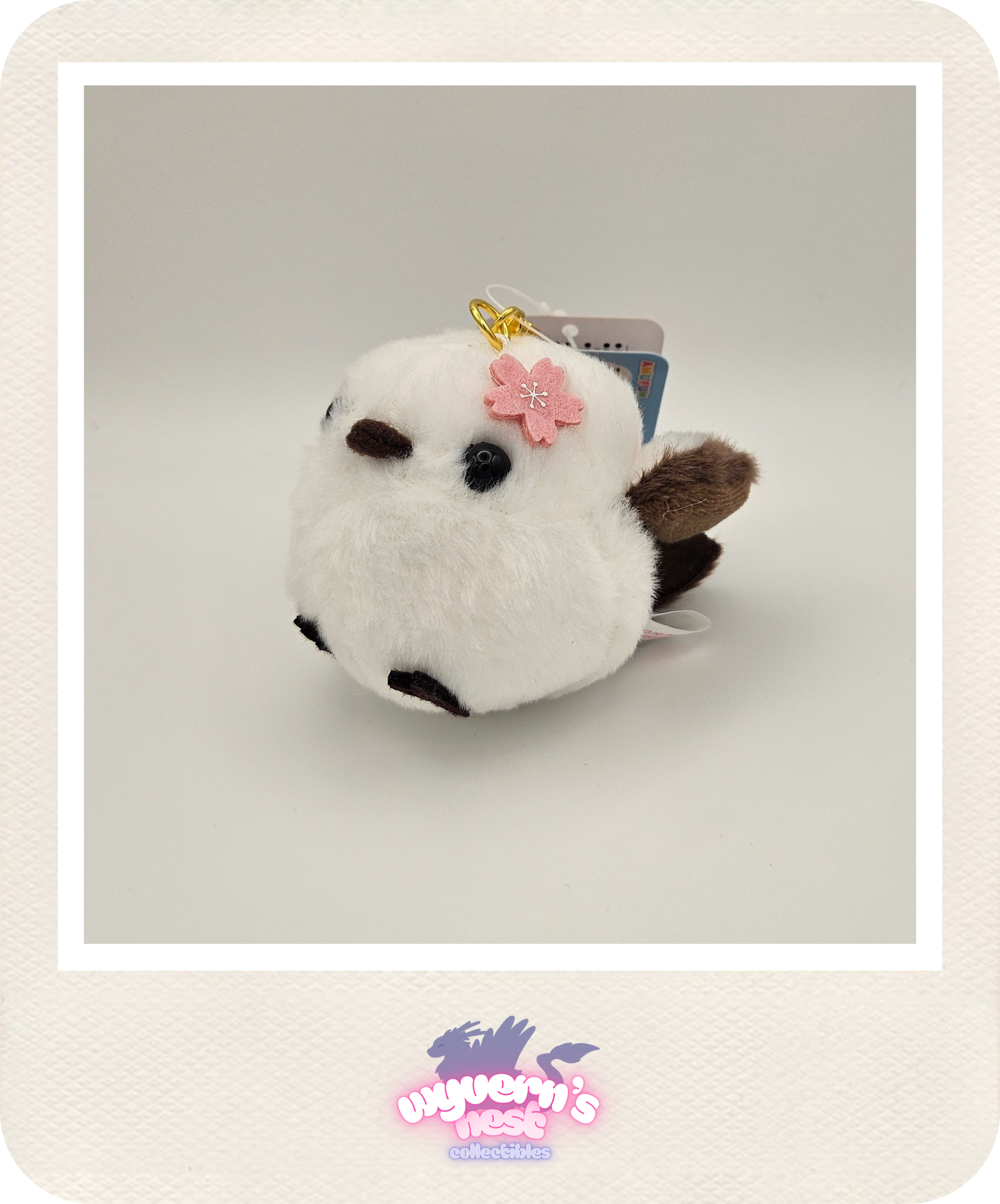 White plush toy with a pink bow on a light gray background