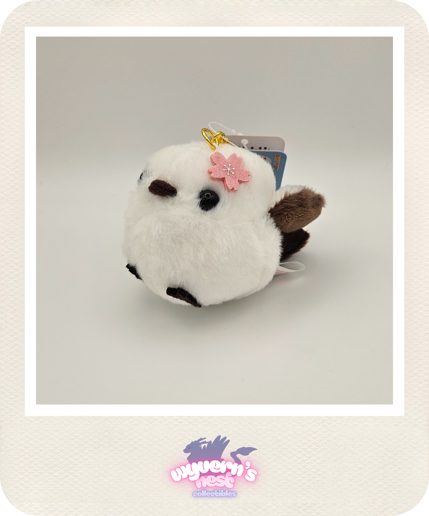 White plush toy with a pink bow on a light gray background