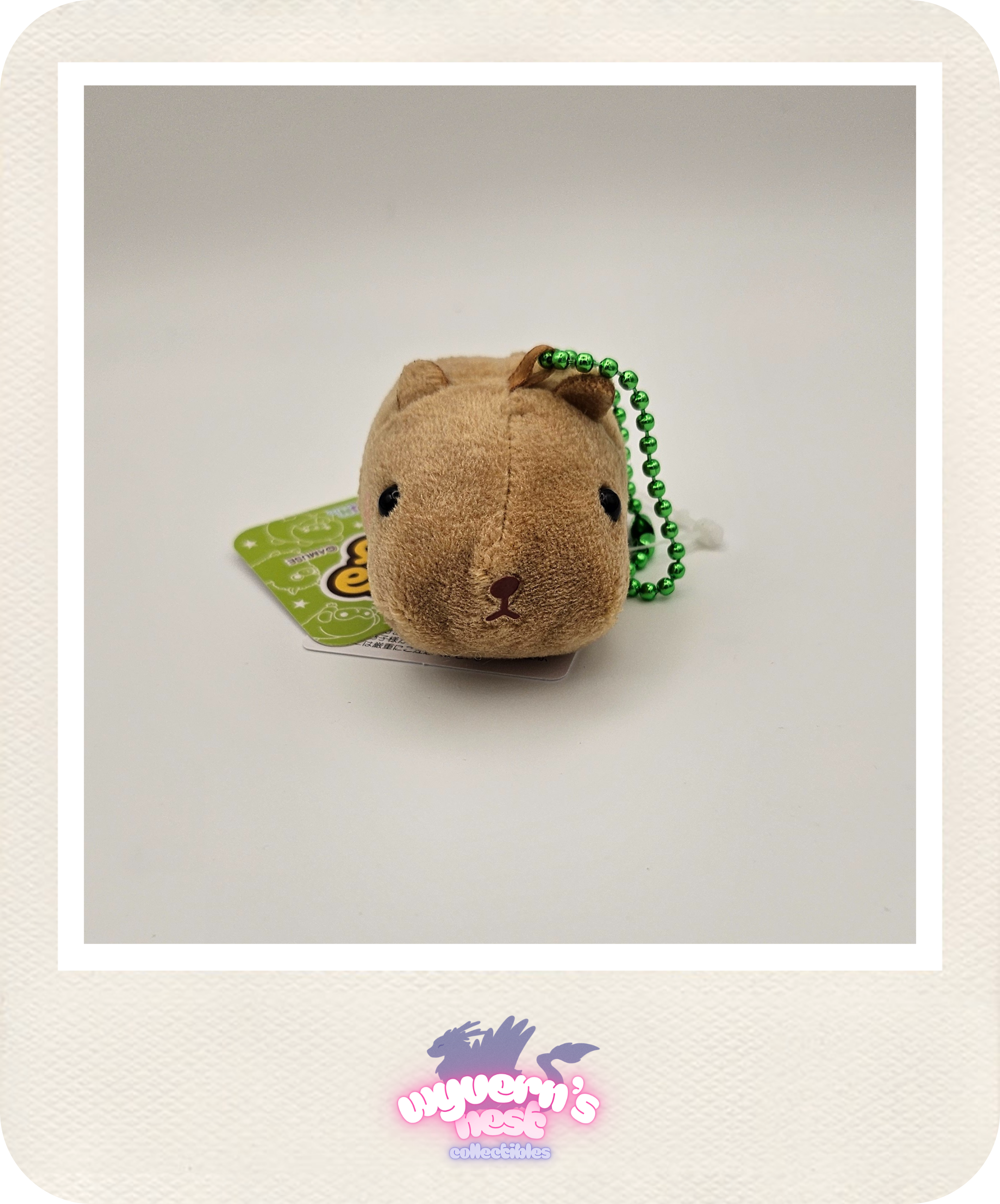 Small brown plush toy with a green bead chain on a white background