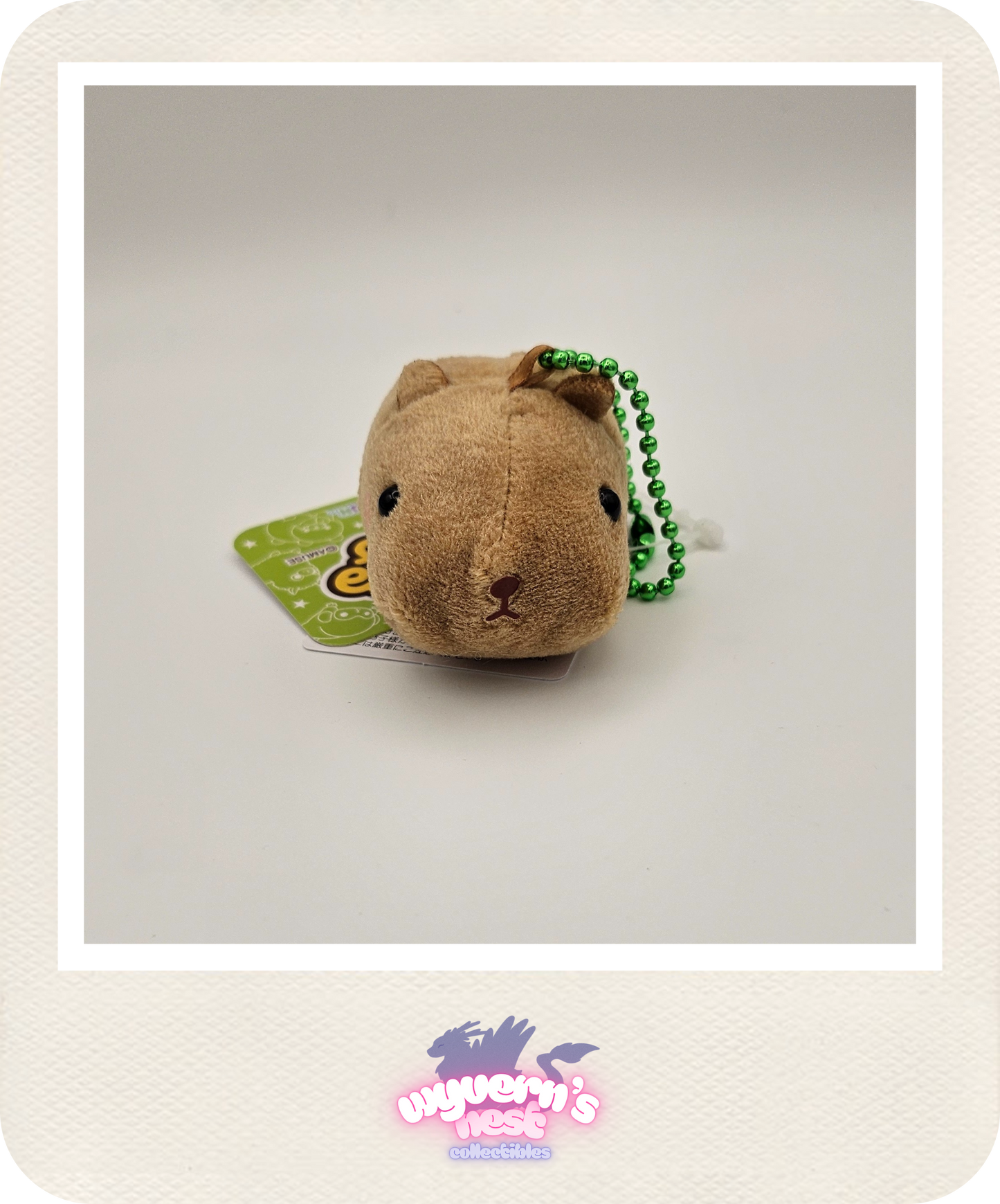 Small brown plush toy with a green bead chain on a white background