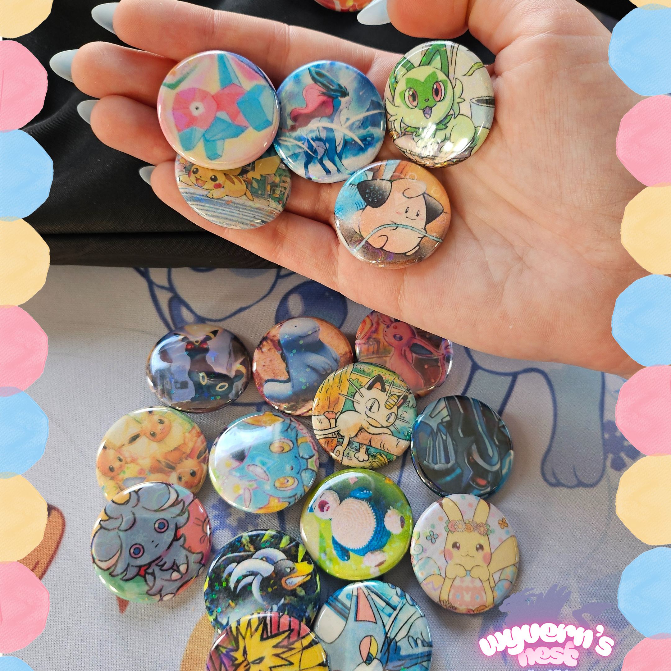 Hand holding colorful buttons with various designs, including pokemon characters, against a multicolored circular border.
